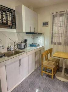 uma cozinha com armários brancos, um lavatório e uma mesa em Baguio De Bisita em Baguio