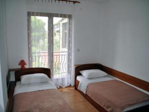 two beds sitting in a room with a window at Apartments Ukić in Tribunj