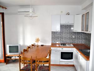 a kitchen with a table with chairs and a television at Apartments Ukić in Tribunj