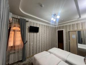 Un dormitorio con una cama y un televisor en la pared. en Boutique Hostel, en Samarkand
