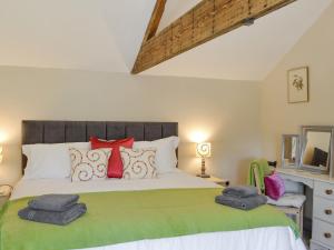 ein Schlafzimmer mit einem großen Bett mit roten Kissen in der Unterkunft Blackcurrant Cottage At Stanton Ford Farm in Baslow + 6 Fotos