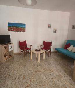 a living room with chairs and a couch and a tv at Happy House Corricella in Procida