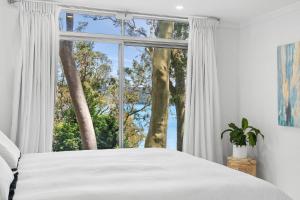 a bedroom with a bed and a large window at Sunset Palms in Palm Beach
