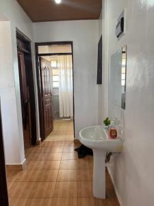 a bathroom with a white sink and a hallway at Eldoret Hideout Cozy 1-Bed Along Kisumu Road Near Tamasha in Eldoret