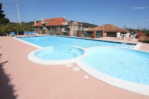 a large swimming pool with chairs and a house at Hotel Liliana Andora citr 9006-0004 in Marina di Andora