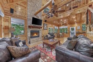 a living room with leather furniture and a fireplace at NEW Forest Sanctuary with Hot Tub Firepit & Creek in Broken Bow