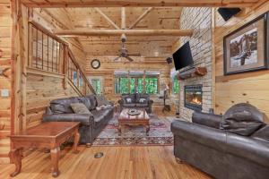 a living room with leather furniture and a fireplace at NEW Forest Sanctuary with Hot Tub Firepit & Creek in Broken Bow