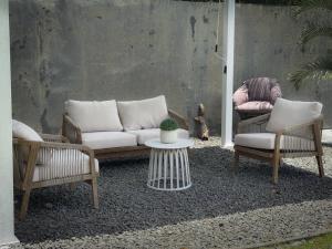 a patio with two chairs and a couch and a table at Villa Jardin secret de la boucan - OFFRE SAISONNIERE ! in Sainte-Rose