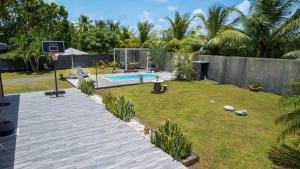 a backyard with a pool and a basketball hoop at Villa Jardin secret de la boucan - OFFRE SAISONNIERE ! in Sainte-Rose