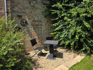 a picnic table and two chairs next to a brick wall at VILLARE8 OG APARTMENT - Moderne Wohnung im Landkreis Gifhorn in Adenbüttel