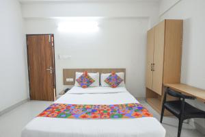 a bedroom with a bed with a desk and a bedspread at FabExpress Golden Grand Inn - Global Village in Bengaluru