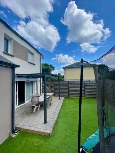 a wooden deck with a bench and a table on the grass at Maison familiale à Nantes Orvault in Orvault
