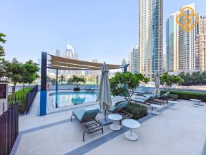 une terrasse avec des chaises et des parasols ainsi qu'une piscine dans l'établissement Keysplease Full Fountain&Burj Views, Grande Tower 14 Downtown, à Dubaï