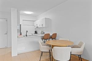 ブリスベンにあるModern Southbank Parklands Apartment Retreatの木製のテーブルと椅子のあるキッチンとダイニングルーム