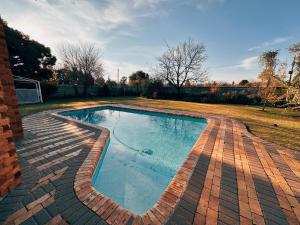 a swimming pool in a yard with a brick pathway at Lemon & Blue Guest House in Welkom