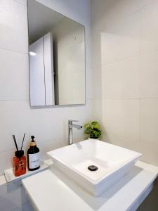 ein weißes Badezimmer mit Waschbecken und Spiegel in der Unterkunft Wonderful Stay BTS Ratchayothin in Bangkok + 20 Fotos