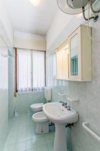 y baño con lavabo, aseo y espejo. en Condominio Brionetta, en Bibione