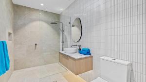 een badkamer met een wastafel, een toilet en een spiegel bij Beach Retreat By Bode in Hawks Nest