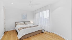 een witte slaapkamer met een bed en een raam bij Beach Retreat By Bode in Hawks Nest +8 foto's