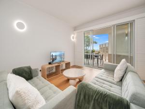 a living room with a couch and a tv at Pandanus Court in Caloundra