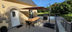 a patio with a table and an umbrella and a grill at Breizh Villa in Landivisiau
