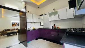 a kitchen with purple cabinets and a living room at Olive Service Apartments - Greater Kailash in New Delhi