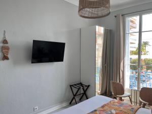 a bedroom with a bed and a television on the wall at Hôtel Eden - La Baigneuse in Juan-les-Pins +26 photos