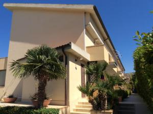 une maison avec des palmiers devant elle dans l'établissement B&B in Residence "...a due passi dalla Scala dei Turchi", à Porto Empedocle