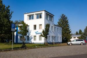 a white building with a car parked in front of it at Pilotenunterkunft Fliegerhorst in Strausberg