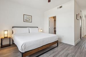 Schlafzimmer mit einem großen weißen Bett und Holzboden in der Unterkunft CozySuites Glendale - Westgate w pool 13 in Glendale