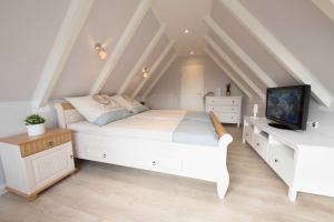a bedroom with a white bed and a tv at Ferienhaus Lüttje Strandhuus in Horumersiel