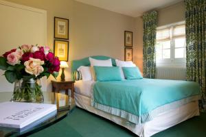 ein Schlafzimmer mit einem Bett und einem Tisch mit einer Blumenvase in der Unterkunft Cazaudehore, hôtel de charme au vert in Saint-Germain-en-Laye