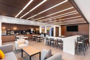 a restaurant with a bar and tables and chairs at Wingate by Wyndham Augusta I-20 in Augusta