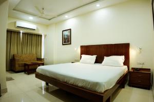 a bedroom with a large bed and a chair at hotel sandhu palace in Jodhpur