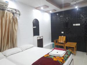 a room with a bed and a table and a tv at Lodge Babul in Kolkata