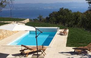 a swimming pool with chairs and an umbrella next to it at Villa Casa Natura Ucka - Opatija by Villas Guide in Mošćenička Draga