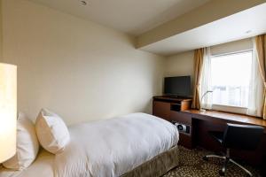 a hotel room with a bed and a desk and a television at ANA Holiday Inn Kanazawa Sky by IHG in Kanazawa