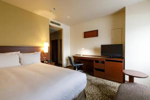a hotel room with a bed and a flat screen tv at ANA Holiday Inn Kanazawa Sky by IHG in Kanazawa
