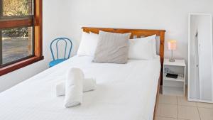 a bedroom with a white bed with white pillows at Seashore Villa by Experience Jervis Bay in Vincentia