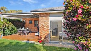a house with a deck with a table and chairs at Seashore Villa by Experience Jervis Bay in Vincentia