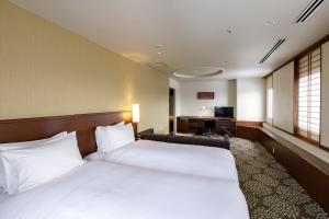 a hotel room with a large bed and a desk at ANA Holiday Inn Kanazawa Sky by IHG in Kanazawa