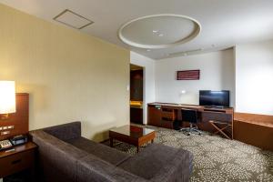 a living room with a couch and a desk with a television at ANA Holiday Inn Kanazawa Sky by IHG in Kanazawa