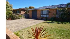 a house with a large yard in front of it at Seashore Villa by Experience Jervis Bay in Vincentia +3 photos