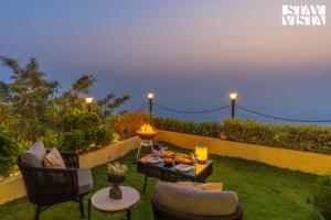 a patio with two chairs and a table with a candle at StayVista at Villa Mirador with BBQ, Bonfire, WiFi in Rishīkesh