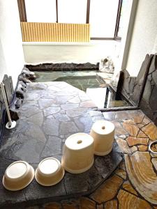 una piscina d'acqua con tre sgabelli di legno sul pavimento di Sanso Tanaka a Yufu Altre 33 foto