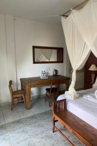 a bedroom with a desk and a bed and a table at Budha House Ubud in Ubud