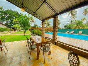 a wooden table and chairs on a patio with a pool at Carambola Resort in Negombo