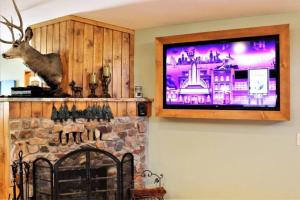 a tv hanging on a wall above a fireplace at Fire Pit & Steps to Village- Village Hideaway in Big Bear Lake