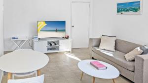 a living room with a couch and a tv and tables at Seashore Villa by Experience Jervis Bay in Vincentia