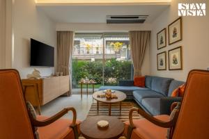 Una sala de estar con un sofá azul y un televisor. en StayVista at Casa Vida Zen with BBQ, Pool, WiFi, en Vagator